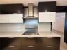 Integrated cooktop with stainless steel range hood, white countertop, and two-tone cabinetry