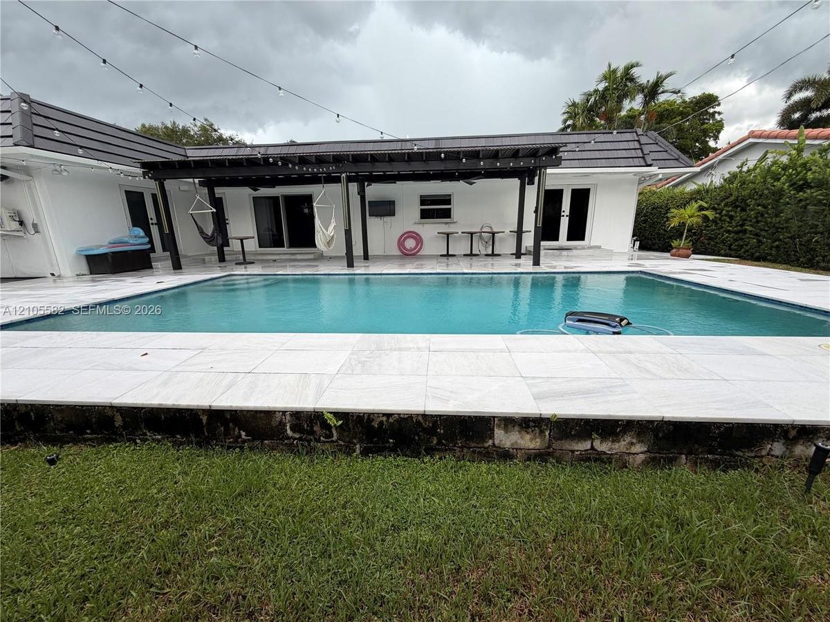In-ground swimming pool with a surrounding stone tile patio