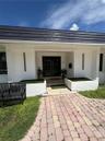 White exterior with a dark tile roof, paved brick walkway, and built-in planters