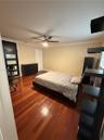 Hardwood flooring throughout, ceiling fan with integrated lighting, crown molding, and a solid door with horizontal glass panels