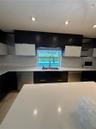 Kitchen featuring white countertops, two-tone cabinetry, recessed lighting, a stainless steel sink with a gooseneck faucet, and integrated stainless s