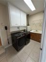 Laundry room with tiled flooring, white upper cabinetry, a utility sink, and wall-mounted shelving