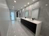 Dual vanity with waterfall countertop, matte black fixtures, integrated sinks, and mirrored medicine cabinets