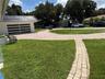 Paved driveway leading to a modern garage door with frosted glass panels, featuring a distinct dark-tiled roof