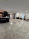 Spacious open-concept interior featuring large format tile flooring, recessed ceiling lighting, and a contemporary entry door