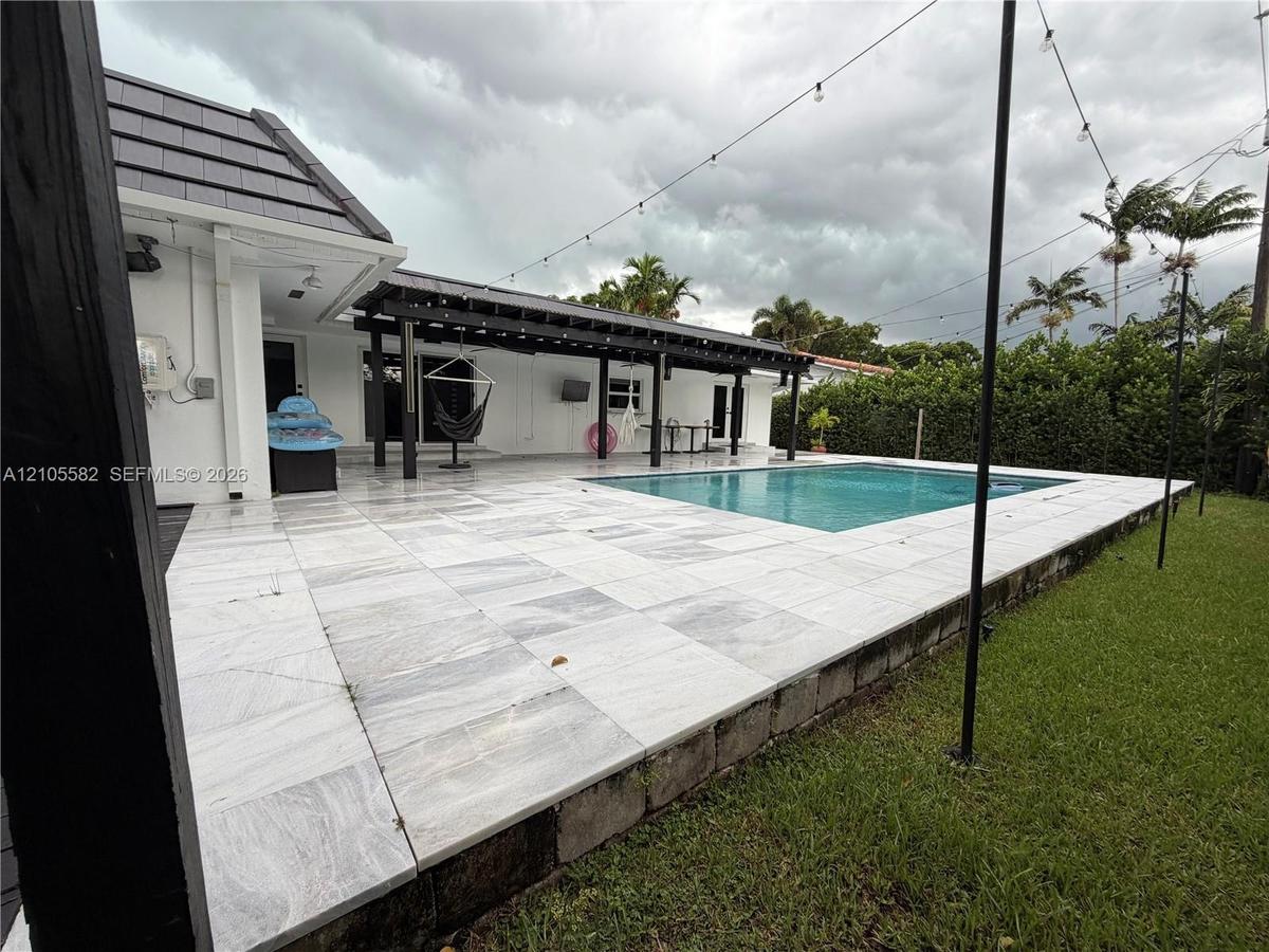 Outdoor swimming pool with a surrounding paved patio and a covered outdoor living area