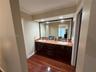 Dual vanity with undermount sinks, stone countertop, wood-finish cabinetry, and a large wall-mounted mirror