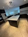Kitchen featuring a central island with white countertop, dark cabinetry, and tile flooring