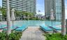 Resort-style circular swimming pool featuring stone paver decking, surrounding palm trees, and manicured landscaping
