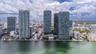 High-rise waterfront complex featuring glass-facade towers, a central swimming pool, and extensive manicured landscaping