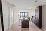 Kitchen featuring a central island with a solid-surface countertop, dark wood-finish cabinetry, built-in appliances, and light wood-finish flooring th
