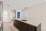 Kitchen island featuring dark wood-finish cabinetry, a white countertop, an integrated stainless steel undermount sink, and a high-arc faucet, complem