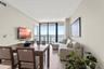 Living area with wood-finish flooring, floor-to-ceiling glass sliding doors, and a covered balcony overlooking the water