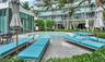 Circular swimming pool surrounded by a stone-paved deck, landscaped garden beds, and palm trees