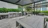 Outdoor kitchen featuring stainless steel built-in appliances, concrete-finish countertops, pergola-covered terrace, and wood-finish decking