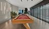 Open-concept recreational space featuring wood-finish flooring, vertical wall-mounted accent lighting, and a series of floor-to-ceiling structural fin