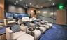 Tiered seating platform with carpeted finish, recessed ceiling lighting, wall-mounted sconces, wood-paneled wall accents, and built-in projection syst