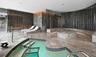 Spa area featuring stone-clad flooring and walls, curved built-in stone seating with integrated ambient lighting, circular raised stone platform, and 