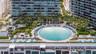 Circular swimming pool surrounded by paved decking, manicured landscaping, mature palm trees, and an integrated hot tub