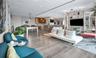 Open-concept interior featuring wood-finish flooring, floor-to-ceiling built-in shelving, a kitchen island with bar seating, and recessed lighting