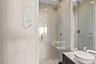 Walk-in shower with floor-to-ceiling tile, frameless glass enclosure, and a ceiling-mounted rainfall showerhead, accompanied by a floating vanity feat