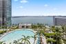 Curved swimming pool with paved decking, landscaped perimeter, and expansive water backdrop