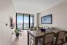 Neutral wall tones, wood-finish flooring, floor-to-ceiling glass sliding doors, and a private balcony featuring a metal railing