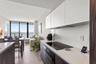 Modern kitchen featuring flat-panel cabinetry, light-toned countertops, a glass-ceramic cooktop, and wood-finish flooring with floor-to-ceiling window