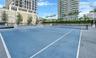 Hard-court tennis facility featuring blue acrylic surfacing, white court lines, perimeter fencing, and integrated pole-mounted lighting