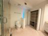 Bathroom featuring a glass-enclosed shower, tile flooring, built-in open shelving, and white cabinetry with a light-toned countertop