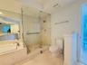 Bathroom featuring a tiled shower stall with a glass enclosure, built-in soaking tub with stone surround, wall-to-wall vanity mirror, and neutral tile