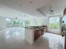 Open concept kitchen featuring stone countertops, wood-finish cabinetry, stainless steel appliances, large-format tile flooring, and floor-to-ceiling 