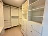 Custom closet featuring white built-in cabinetry, floor-to-ceiling shelving, integrated hanging rods, and large-format tile flooring