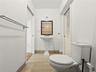 Pedestal sink with a dark-framed rectangular mirror, neutral-toned tile flooring, and a wall-mounted metal towel bar