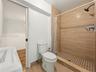 Bathroom featuring a walk-in shower with wood-finish tile surround, geometric patterned tile flooring, and a wall-mounted shower head