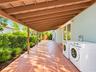 Covered patio featuring terracotta-style tile flooring, wood-beam ceiling structure, and integrated exterior wall lighting
