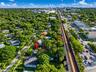 Aerial perspective featuring a residential lot with mature canopy trees, extensive landscaping, and proximity to major thoroughfares and urban skyline