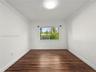 Interior space featuring wood-finish flooring, white walls, crown molding, and a dual-pane sliding window