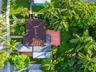 Aerial view of a property featuring a tile roof, an elevated wooden deck, mature palm trees, and extensive landscaping