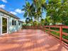 Expansive wooden deck featuring horizontal rail fencing, mature palm trees, and structural exterior access