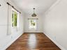 Room featuring wood-finish flooring, crown molding, dual windows, and a decorative pendant light fixture