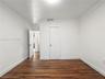 Interior space featuring wood-finish flooring, crisp white walls, crown molding, and solid-core interior doors with metallic hardware