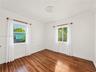 Room featuring wood-finish flooring, dual windows with decorative molding, and crown molding