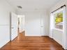 Interior space featuring wood-finish flooring, crown molding, white shaker-style doors, and natural light through a side window