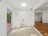 Interior space featuring large-format neutral floor tiling, wood-finish flooring, crown molding, a flush-mount ceiling light fixture, and a glass-pane