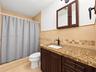 Bathroom featuring stone-surface vanity with rectangular undermount sink, dark wood-finish cabinetry, built-in medicine cabinet, matte black hardware,