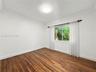 Room featuring wood-finish flooring, crown molding, and a sliding window with outdoor greenery exposure