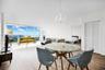 Open-concept living space featuring floor-to-ceiling windows, wood-finish flooring, a crystal chandelier, and louvered closet doors