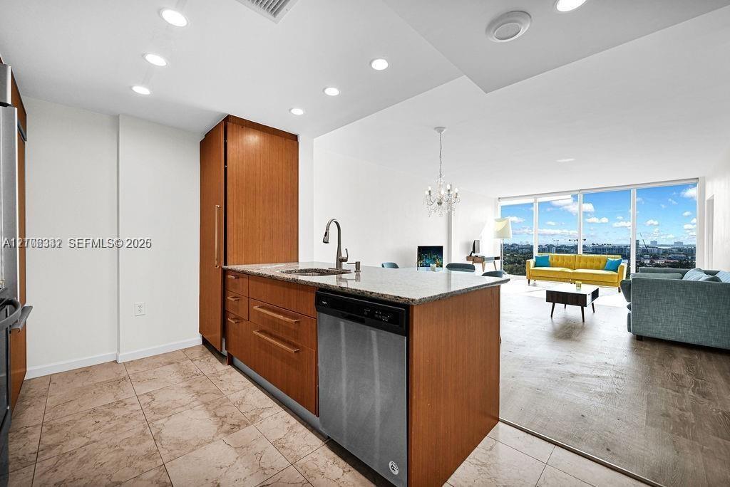 Kitchen featuring wood-finish cabinetry, stone-surface countertops, stainless steel appliances, recessed lighting, and tile flooring