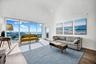 Living area featuring vaulted ceilings, floor-to-ceiling glass windows, and wood-finish flooring